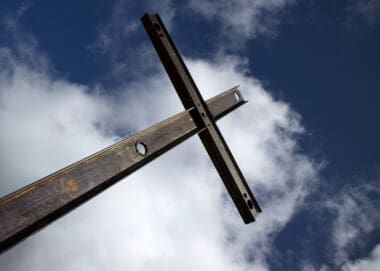 A picture of cross on a cloudy sky background. A cross that is reperesenitive of the cross that Jesus died on.